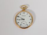une montre de poche en or sur une surface blanche
