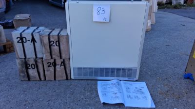un réfrigérateur blanc posé à même le sol, à côté d'une pile de cartons