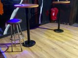 deux tabourets et une table dans une pièce où est accroché un tableau au mur