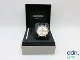 La montre se trouve dans une boîte contenant un stylo et un stylo.