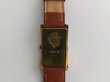 a close up of a watch on a white surface with a brown strap