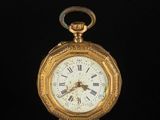 a gold pocket watch with roman numerals on the face