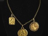 a gold plated necklace with three charms on a black mannequin