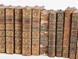 several old books are lined up in a row on a white surface