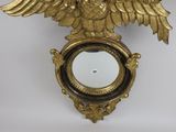 a gold clock with an eagle on it hanging on a wall