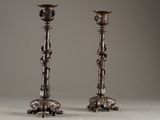 pair of antique silver candlesticks on stand against a gray background