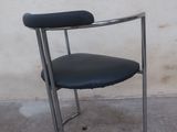 a black chair with a black seat and a white wall