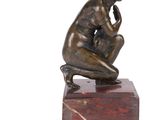 statue of a man sitting on a marble block with his hand on his chin
