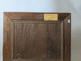 an old picture frame with a label on it sitting on a table