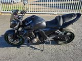 a black motorcycle parked in a parking lot near a fence