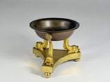 an image of a small brass bowl on a stand on a white surface