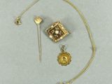 une photo d'un collier en or avec une broche et d'autres objets