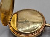 a gold pocket watch sitting on a gray surface