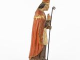 an old statue of a man in a red robe holding a staff