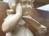 a statue of a little girl holding her hand to her face