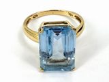a close up of a blue topaz ring on a white surface