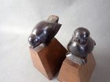 two figurines of a bird and a fish on a wooden stand