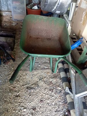 une brouette verte au milieu d'un tas de terre