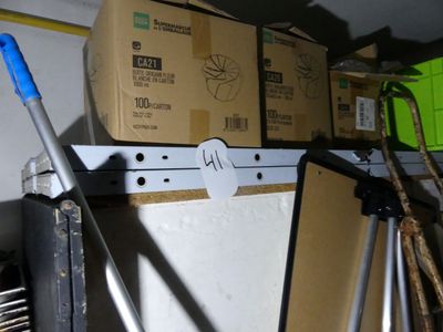 une pile de cartons posée sur une étagère, à côté d'une serpillière