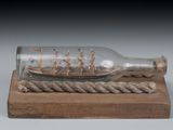a ship in a glass bottle on a wooden base