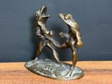 bronze statue of two men fighting with each other on a wooden table