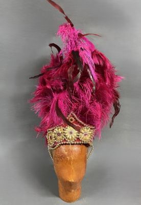 chapeau rose à plumes, orné d'une bordure dorée et de perles, monté sur une coiffe en bois