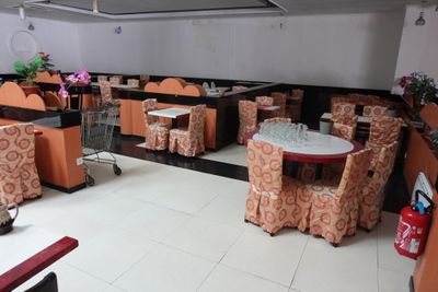 Dans un restaurant, les tables et les chaises sont alignées et recouvertes de nappes orange.