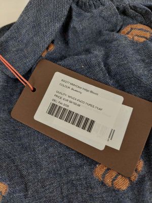 a close up of a label on a blue shirt with orange flowers on it
