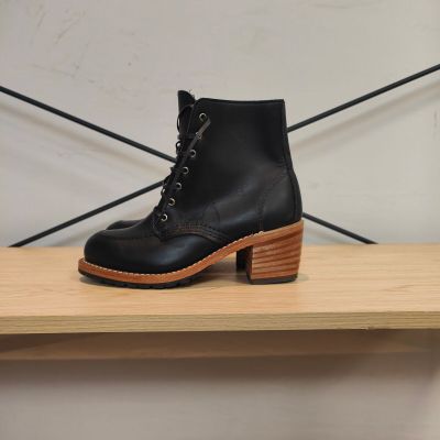 une paire de bottes noires posée sur une étagère en bois