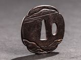 a close up of a small metal tsuba on a table
