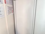 two white refrigerators in a room with a red wall