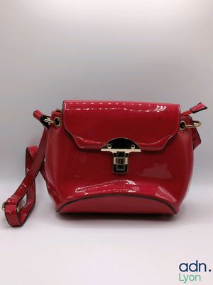the red purse is sitting on a white surface