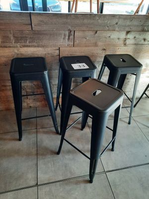 trois tabourets noirs posés devant un mur en bois