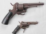 une paire de vieux revolvers posés l'un à côté de l'autre sur une surface blanche