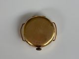 a close up of a gold plated pocket watch on a white surface