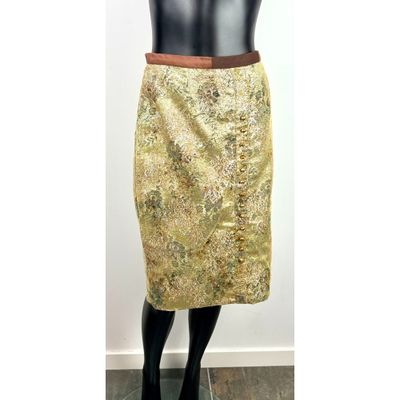 Le mannequin porte une jupe dorée avec une ceinture marron.