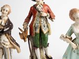 three figurines of people are standing next to each other on a white surface
