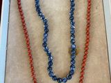 deux colliers dans une boîte, dont un collier composé de perles rouges et bleues