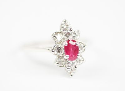 a close up of a ring with a ruby stone surrounded by white diamonds