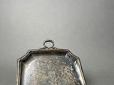 an old silver tray with a handle on a gray surface