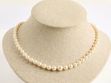 collier de perles présenté sur un mannequin devant un fond blanc