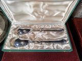 three silver spoons in a case on a table