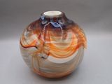 une photo d'un vase en verre orné de volutes orange et blanches