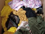 a cardboard box filled with clothes and clothes on the floor