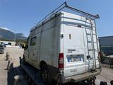 a white van parked in a parking lot with mountains in the background