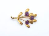 un gros plan d'une broche en or ornée de pierres violettes
