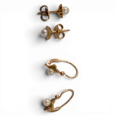 three pairs of gold earrings with pearls on them on a white surface
