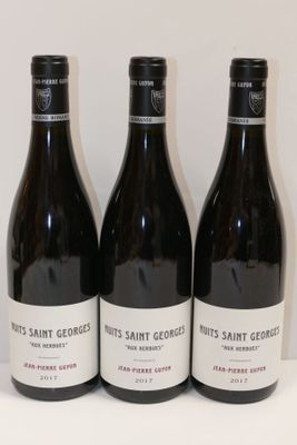 trois bouteilles de vin sont alignées sur une surface blanche