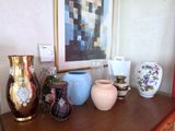 many vases sitting on a wooden table with a painting in the background