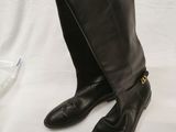 the person is holding a pair of black boots on a white table